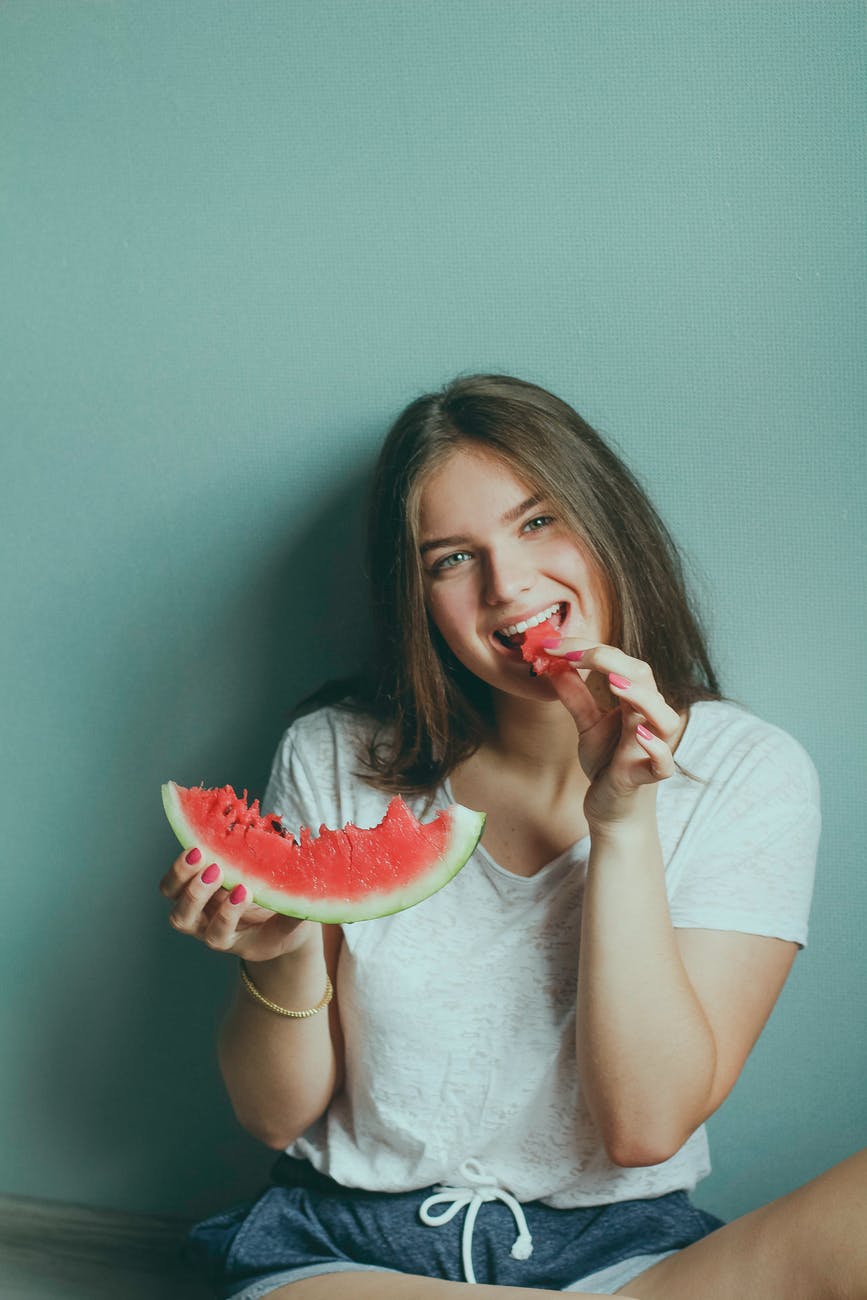 woman wearing white shirt eating watermelon