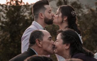 elegant ethnic newlyweds and parents kissing on wedding day outdoors